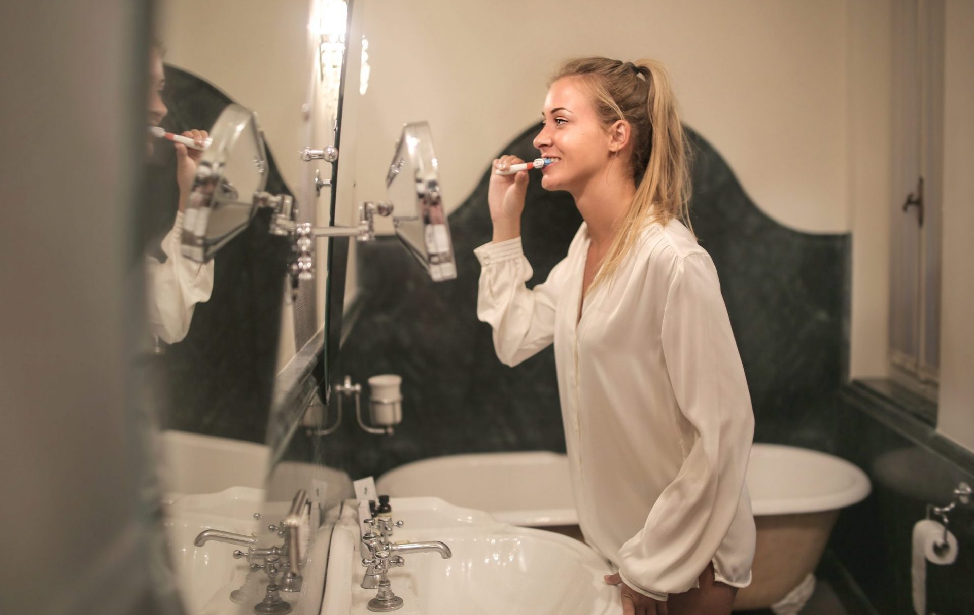 girl brushing teeth in mirror