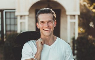 Man smiling in front of a house
