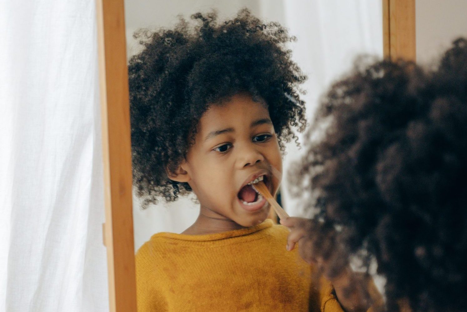 kid brushing teeth in mirror