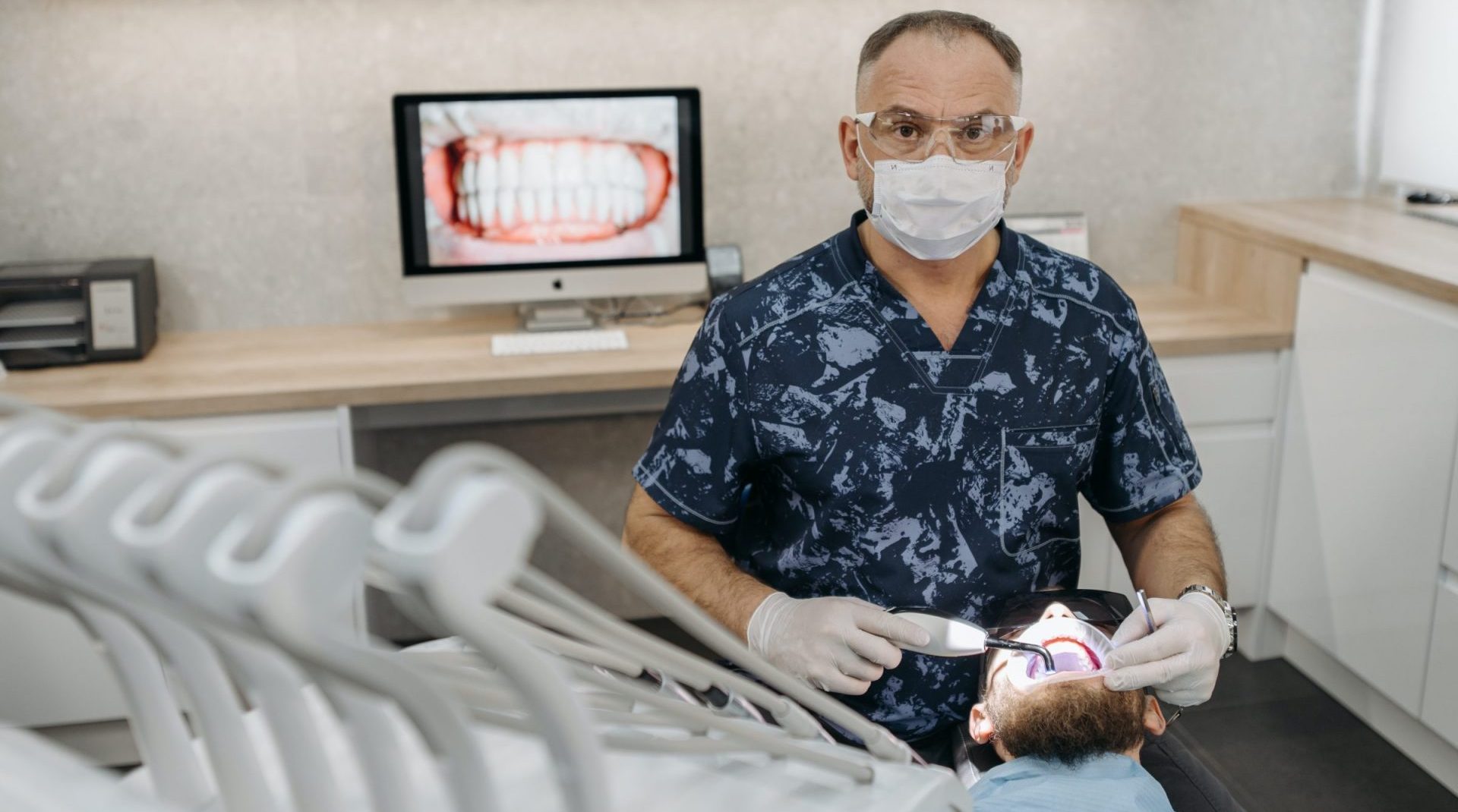 dentist in blue floral shirt working on patient