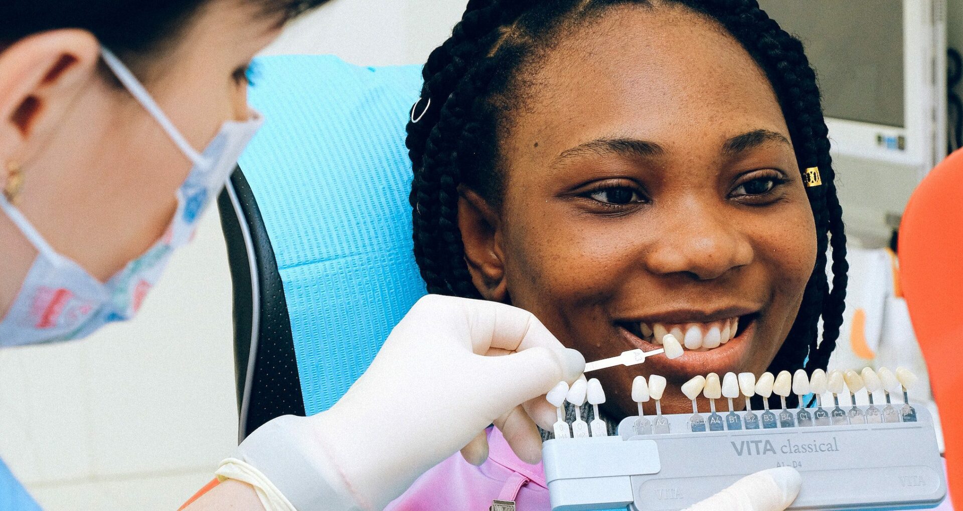 dentist holding up porcelain veneers to a patient's mouth