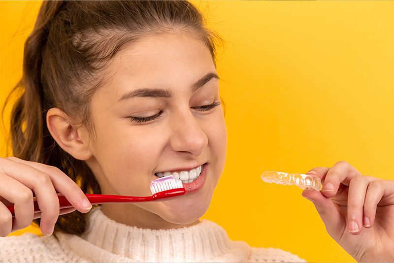 Teenager brushing teeth holding invisalign