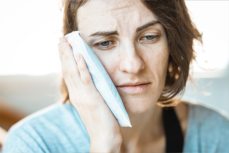 Woman holding cold compress on cheek
