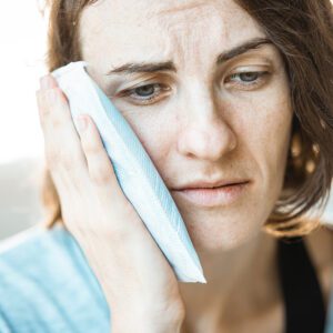 woman holding ice pack to cheek