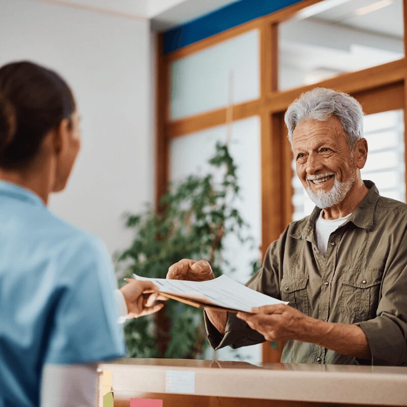 older man taking his medical paperwork from dental hygienist