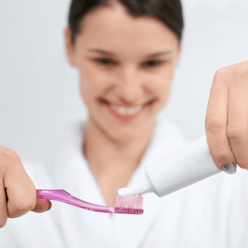 woman putting tooth paste on tooth brush woman putting tooth paste on tooth brush