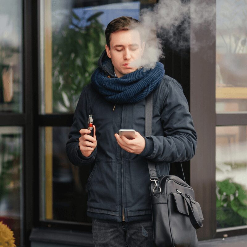 smoking a vape, man wearing black jacket