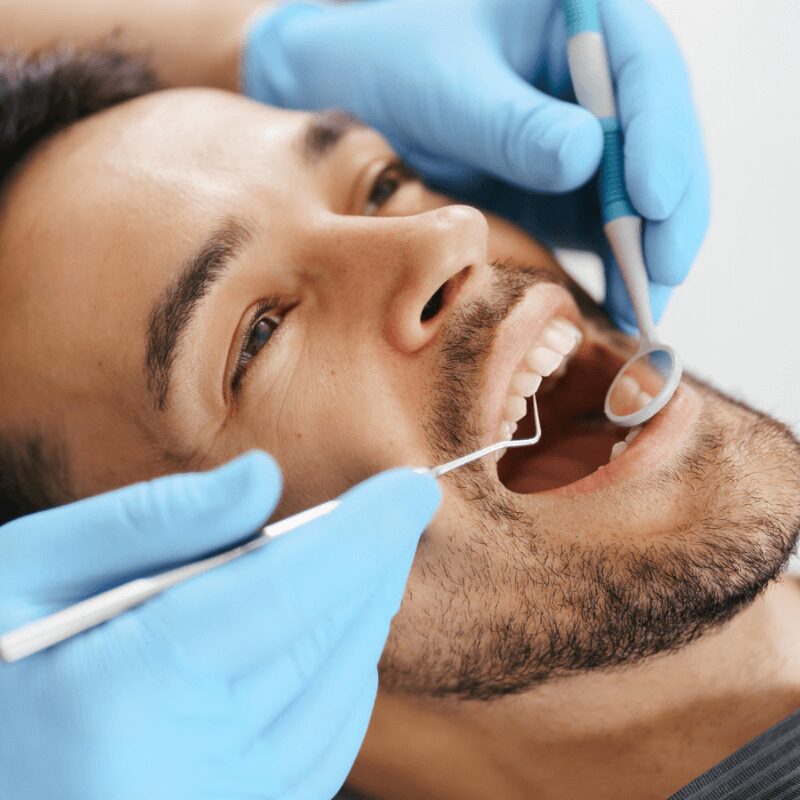 yonng man getting his teeth and gum examined, oral checkup