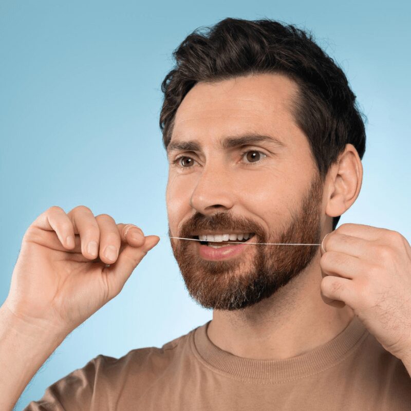 young man flossing his teeth, healthy oral hygiene habit
