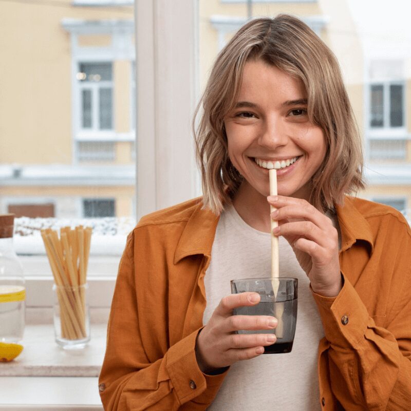 woman smiling using zero waste straw to drink lemon juice woman smiling using zero waste straw to drink lemon juice