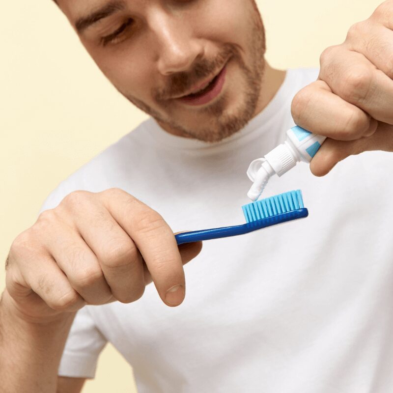 young man putting toothpaste on his toothbrush to clean teeth