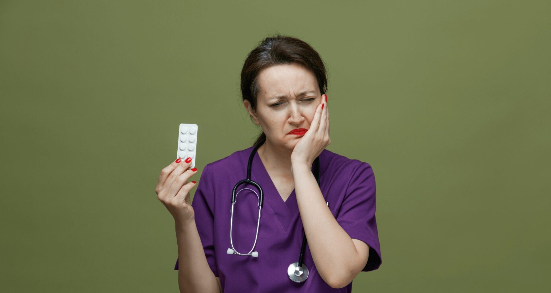 female doctor holding antibiotics while hodling her jaw because of tooth infection pain