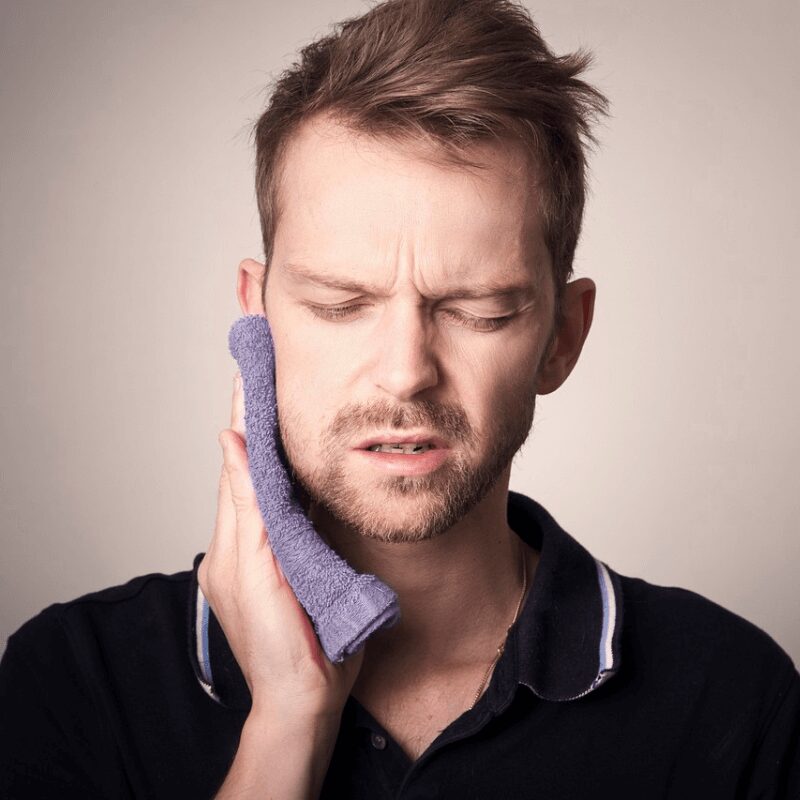 young man feeling swollen tooth due to chewing hard ice young man feeling swollen tooth due to chewing hard ice