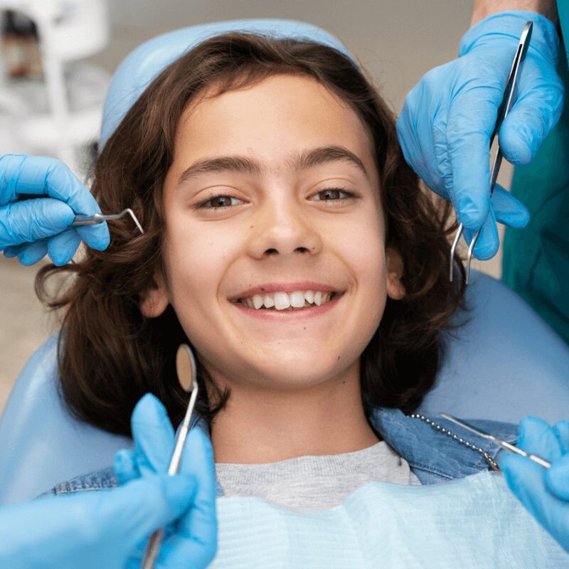 kid sits at the dentist chair for dental cleaning