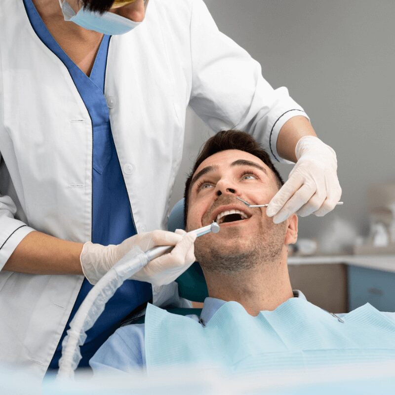 man smiles at the dentist during dental cleaning procedure